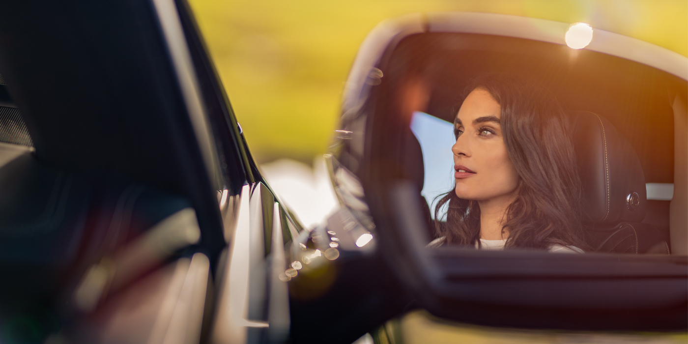 Bentley Mougins profile of dark haired woman's face in mirror of Bentley car in sunlight