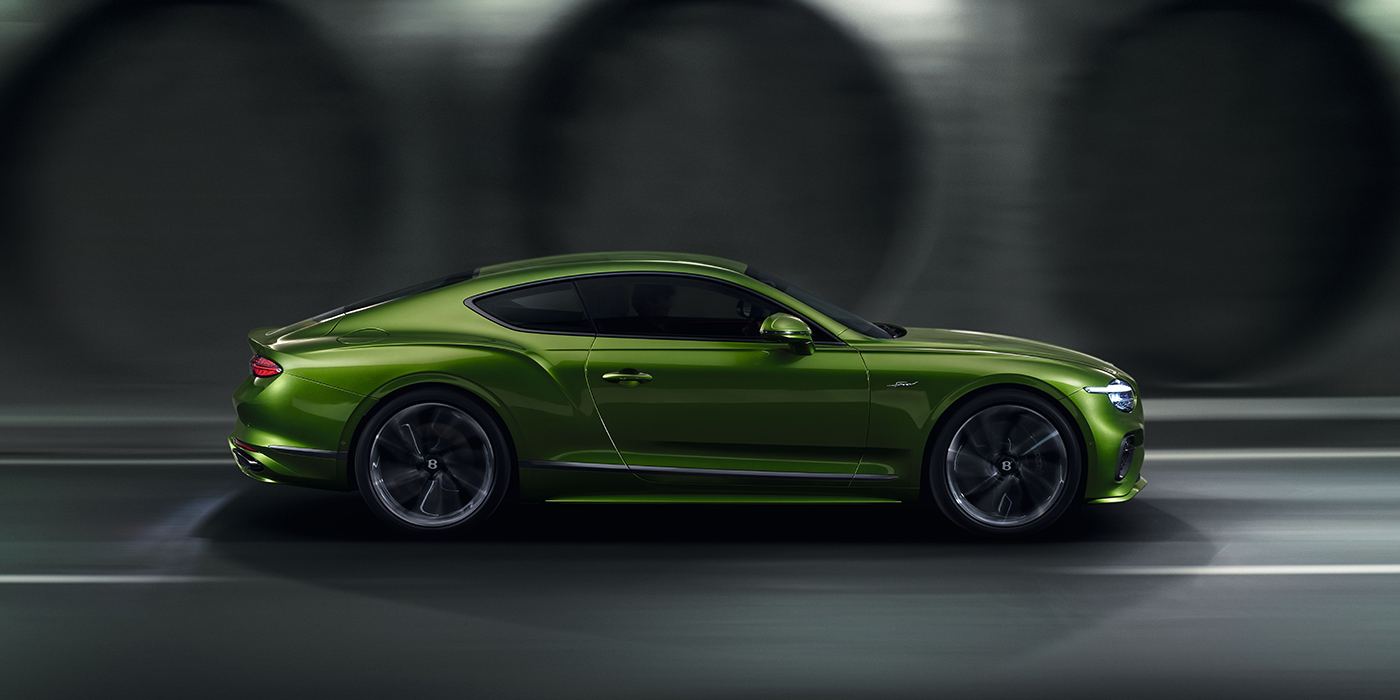 Bentley Mougins Bentley Continental GT coupe in Tourmaline Green paint driving in profile on a dark road