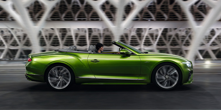 Bentley Mougins Bentley Continental GTC Speed convertible side profile in Tourmaline Green paint driving dynamically on a bridge at night