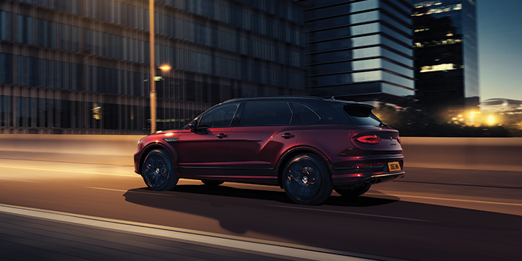 Bentley Mougins Bentley Bentayga Extended Wheelbase Mulliner SUV in Cricket Ball red paint driving dynamically in city at night
