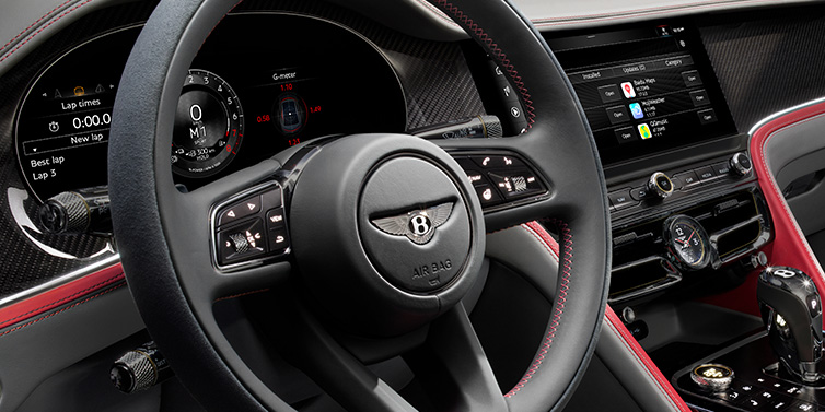 Bentley Mougins Bentley Flying Spur Speed sedan front interior detail showing steering wheel and driver screens surrounded with Hotspur red and Gravity Grey hides